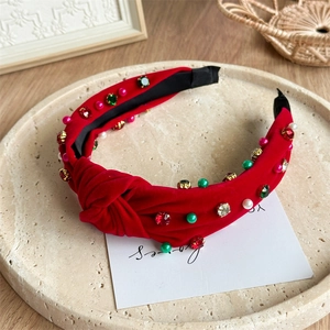 Détail d'un serre-tête noué en velours rouge avec strass colorés et perles blanches