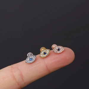 Detailed comparison of silver, gold, and rose gold evil eye ear studs held on fingertips