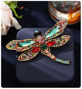 Close-up of a luxury dragonfly brooch with colorful crystals on a velvet jewelry box