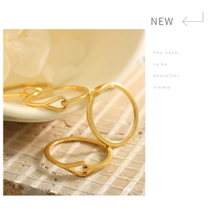 Detailed view of three 18K gold plated heart rings on a textured stone and ceramic base