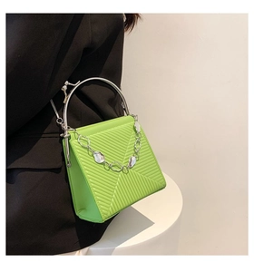 Detail of neon green textured handbag with silver metal handle and chain on model