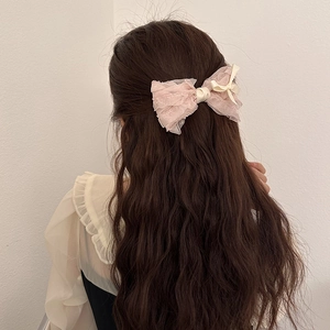 Sweet ballet style pink lace ribbon bow hair clip worn on long wavy brunette hair