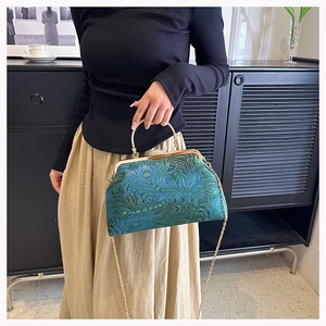 Detail of vintage style handbag with teal peacock feather texture and gold metal frame