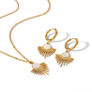 Detailed view of gold stainless steel sunburst necklace and earring set with white inlay