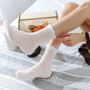 Detail of pink coral fleece thermal socks with fluffy white trim in a cozy home setting