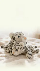 Close-up of cute plush snow leopards with blue eyes on a soft white furry blanket