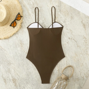 Flat lay of a brown high-cut swimsuit with thin straps on a stone background