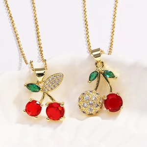 Detail of cherry pendant necklace with red and green zircons on a gold chain
