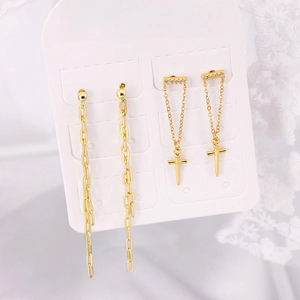 Macro view of gold-plated tassel chain and zircon-inlaid cross earrings on card