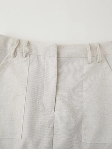 Detailed macro view of the linen texture and waistband stitching on off-white shorts