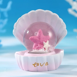 Detailed close-up of pink shell base with glowing glass ball and sea star decor