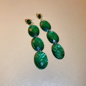 Macro shot of long geometric emerald green faceted crystal drop earrings with gold settings