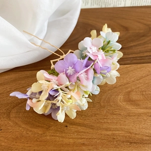 Detail of delicate handmade silk flowers on a golden wavy metal hairpin for wedding