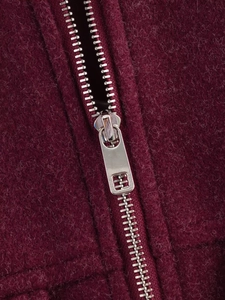 Macro shot of silver zipper on dark burgundy wool coat showing high-quality fabric texture