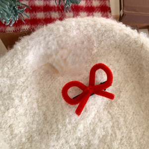 Detailed view of red plush bow hair clip on a white fleece beret for festive outfits