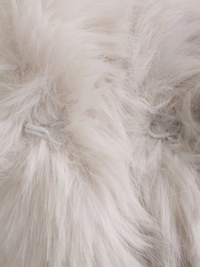 Dettaglio macro della pelliccia sintetica e asole elastiche sul cappotto di peluche