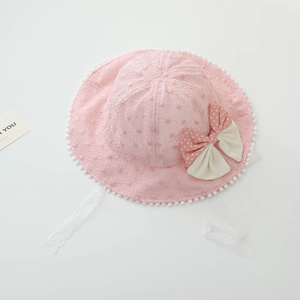 Detail of pink lace baby sun hat with white pom-pom trim and polka dot bow accent