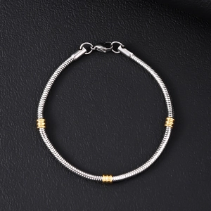 Close-up of Cuban chain bracelet with gold beads on black leather texture
