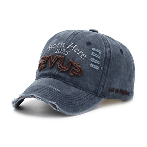 Détail d'une casquette en denim gris délavé avec broderie 3D et finitions usées