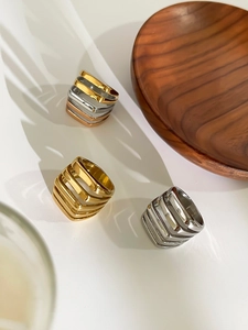 Detailed view of hollow geometric layered rings in gold and silver with soft shadow
