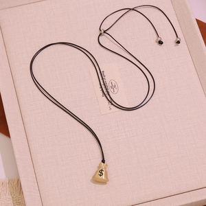 Close-up of golden money bag pendant with dollar sign on black cord necklace