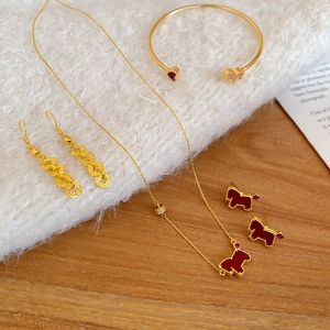 Close-up of golden jewelry set with red zircon horse motifs on white faux fur and wood