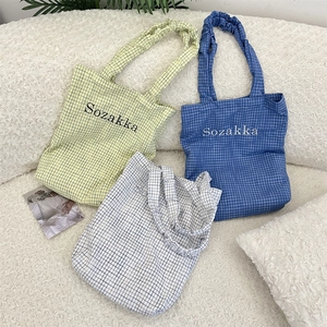 Detail of checkered canvas tote bags with ruched handles and Sozakka embroidery