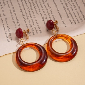 Détail macro de boucles d'oreilles clips en résine ambre avec motif marbré rétro et vis or