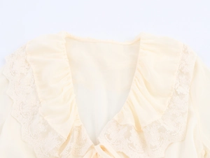 Detail of the V-neckline with delicate lace trim and ruffle edges on a light yellow dress