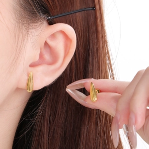 Vue détaillée de petites boucles d'oreilles plume dorées avec des textures fines et fermoir