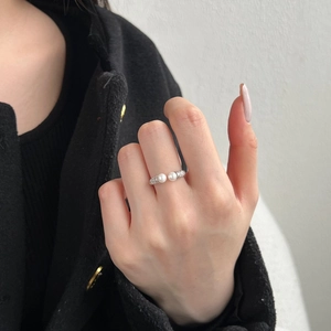 Detailed view of sterling silver open ring featuring two white pearls on a model hand
