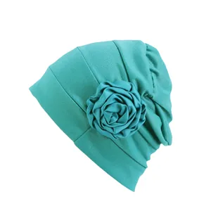 Détail du bonnet turban plissé turquoise avec une grande fleur en tissu faite main
