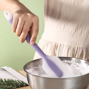 Silicone spatula for baking and mixing cream in a metal bowl with purple handle