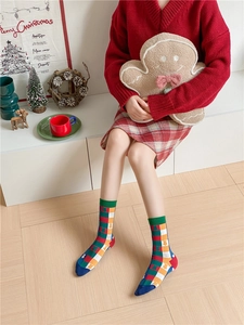Close-up of festive red Christmas socks with colorful geometric patterns on model