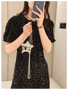 Star-shaped silver mini crossbody bag with bead chain shown on a black sequin dress