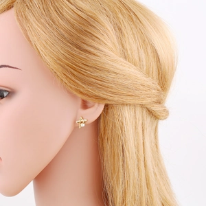 Close-up of a golden star stud earring with a pearl center and zircon details on model
