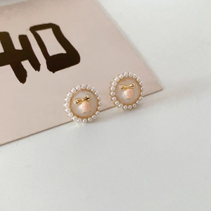 Detail of vintage flower earrings with mini pearls and a golden bow on a calligraphy card