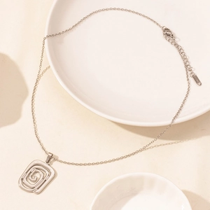 Macro detail of geometric spiral shell pendant with adjustable lobster clasp on steel chain