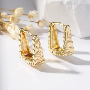 Polished gold geometric earrings with leaf pattern texture on a white background