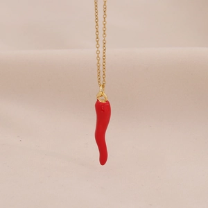 Detail van een gouden roestvrijstalen ketting met een rode emaille chili peper hanger