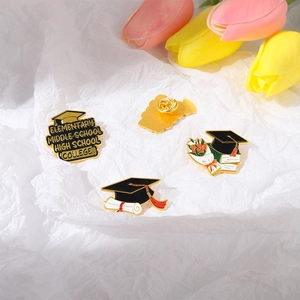 Detail view of graduation enamel pins featuring graduation caps, diplomas and floral books