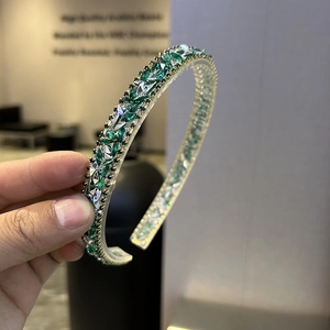 Close-up of luxury Baroque headband with green crystals and rhinestones on gold frame