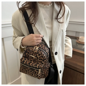Detail of leopard print backpack with gold zippers on a white blazer outfit