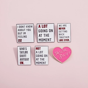 Set of 6 Taylor Swift inspired enamel pins with lyrics on a soft pink background
