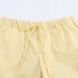 Détail du pantalon à rayures verticales jaunes et blanches avec taille élastique et cordon