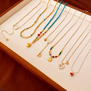 Détails de colliers plaqués or avec pendentifs cœur et gourde dans un plateau à bijoux