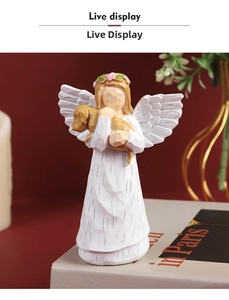 Close-up of hand-painted resin angel figurine holding a yellow dog on a rustic book