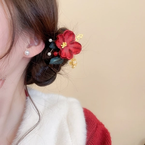 Close-up of Chinese New Year hair clip with red flowers, pearls, and golden metal leaves