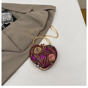 Detailed view of heart-shaped velvet clutch with gold bead floral sequins and metal handle
