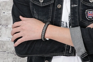 Detail of woven titanium steel bracelet in black and silver on a male model's wrist